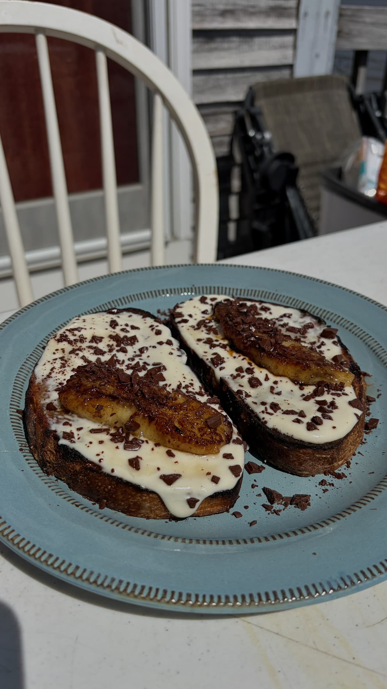 Two slices of brown sugar cinnamon sourdough with whipped ricotta, caramelized banana and chopped dark chocolate